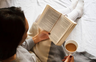 Persona leyendo un libro abierto mientras toman un cafe